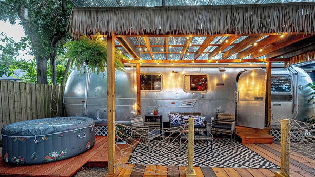 Un espace de vie extérieur accueillant, doté d ’un toit de chaume, d’un jacuzzi et d’une terrasse en bois.