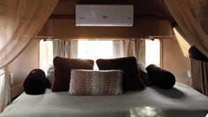 Un lit avec des oreillers, un baldaquin et un appareil de climatisation.