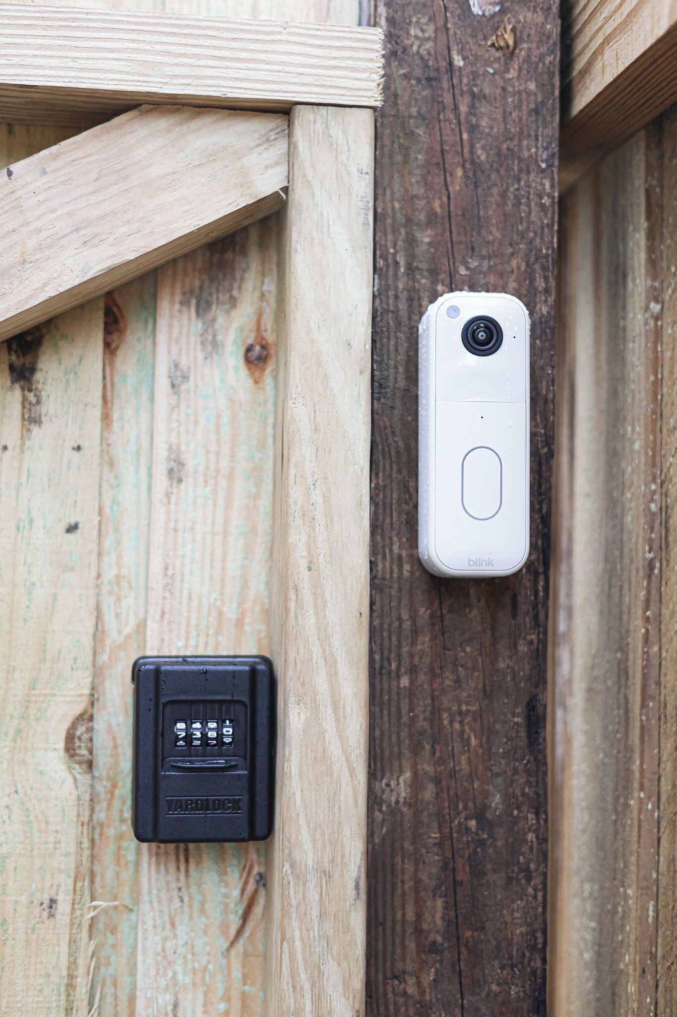 A security camera and a keypad lock on a wooden door.