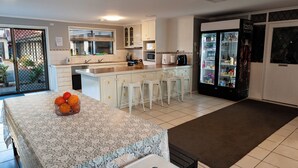 Uma cozinha moderna com armários brancos, uma ilha central com banquetas, uma geladeira e um micro-ondas.