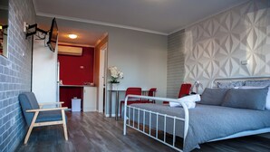Quarto moderno com cama, uma cadeira, uma mesinha e parede vermelha.