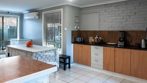 Cozinha com bancada de mármore, armários de madeira e parede de tijolos.