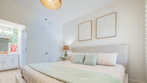 A bedroom with a bed, bedside table, lamp, and a door leading to a bathroom. - Near Epic Universe & Universal, +parking & Netflix (Orlando)