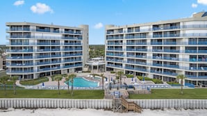 A hotel with multiple floors, balconies, and a swimming pool. - Ebb Tide - 703 your oceanfront dream vacation destination awaits! (New Smyrna Beach)