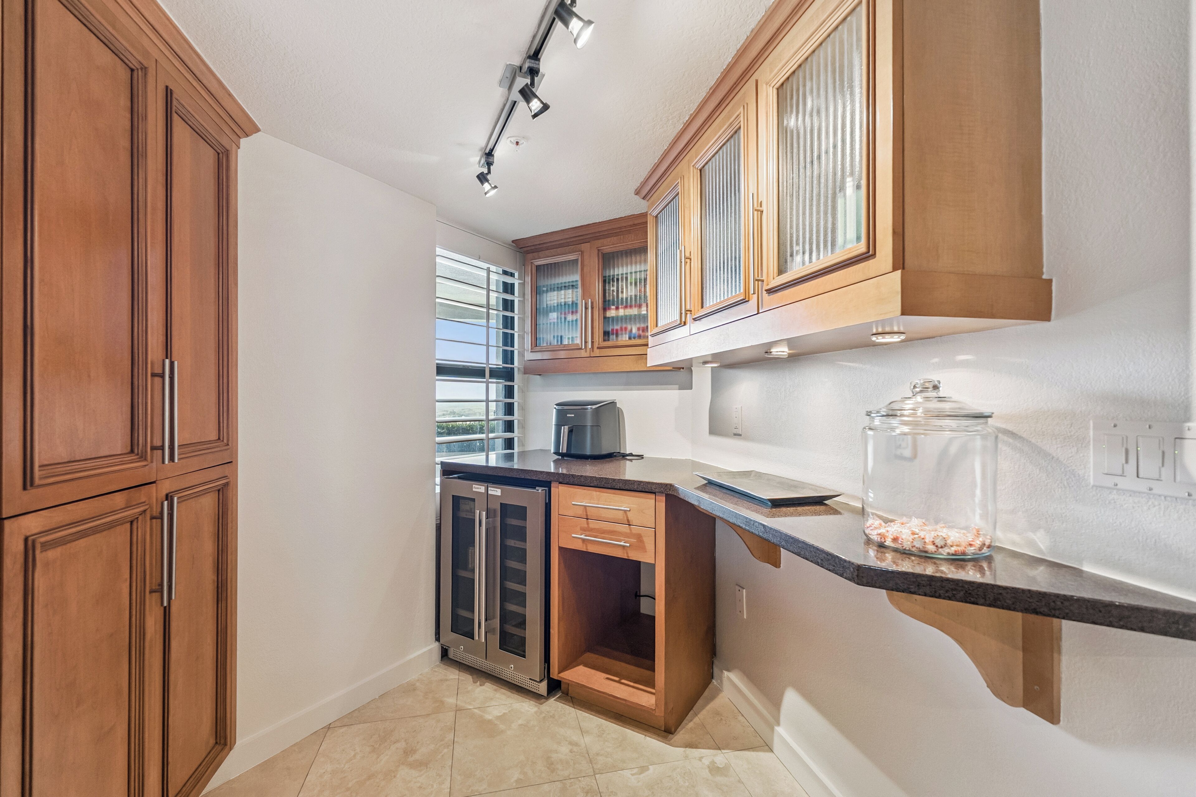 A kitchen with wooden cabinets, a built-in oven, and a countertop with a glass jar.