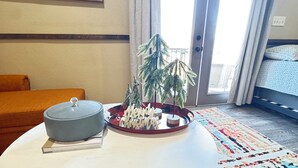 Une pièce avec une table ronde, un petit sapin de Noël et un lit recouvert d’une literie à motifs.