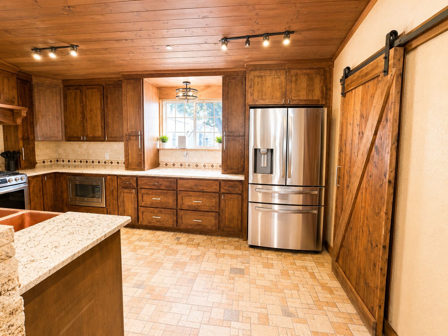 A kitchen with wooden cabinets, a stainless steel refrigerator, a window with plants, and a herringbone-patterned floor.