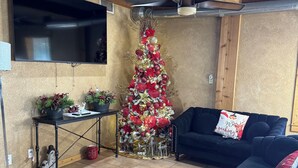 Un salon avec un grand téléviseur à écran plat, un canapé bleu foncé et un sapin de Noël.