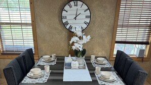 Une table à manger dressée avec des assiettes, des bols et une horloge.