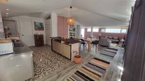 A modern kitchen with a central island, a dining area with a table and chairs, and a living room with a sofa and a TV. - dareddroudj (Algiers)