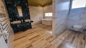 A bathroom with a marble floor, a freestanding bathtub, a toilet, and a sink area with a mirror. - dareddroudj (Algiers)