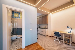 Un apartamento moderno con baño, kitchenette y un espacio de escritorio.
