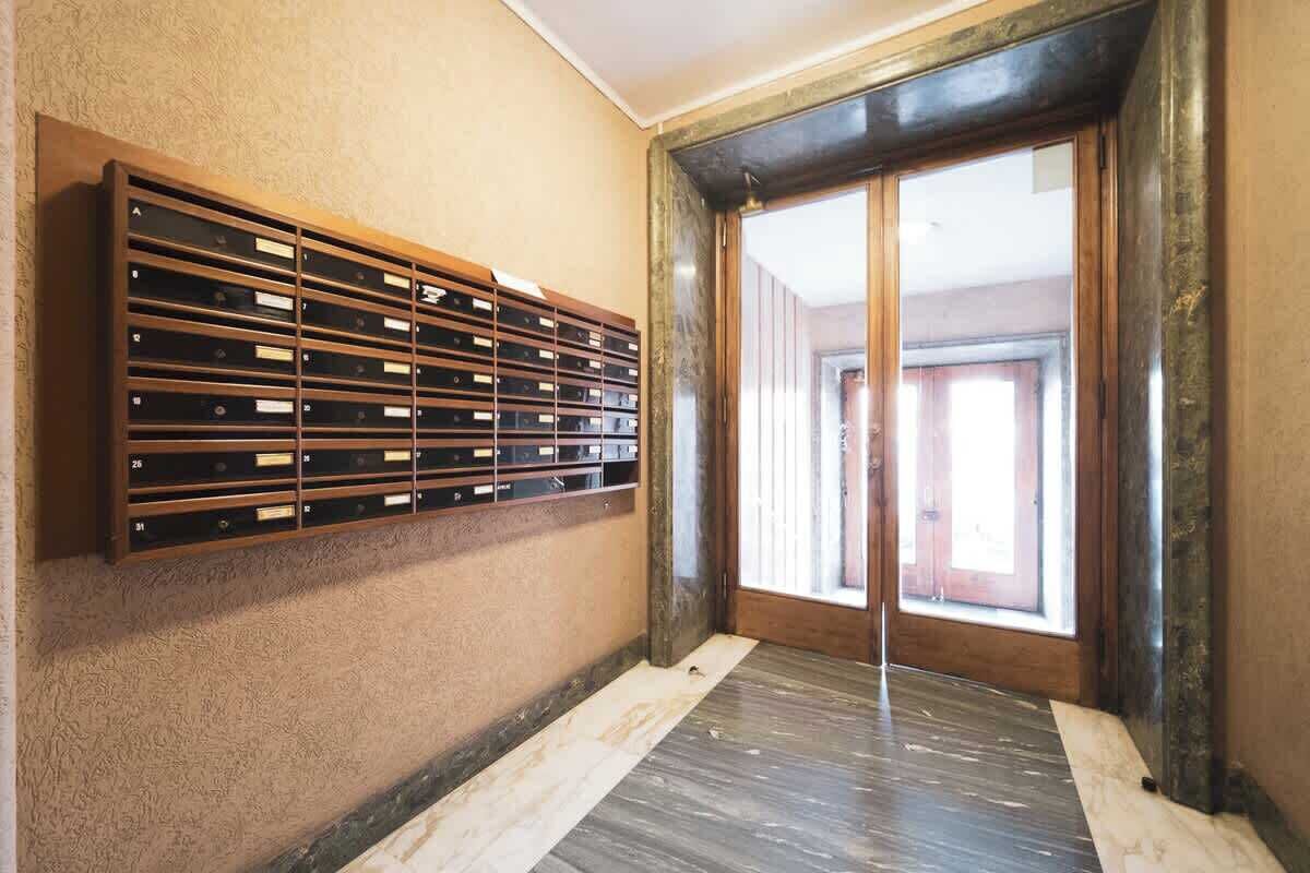 A room with a wooden storage unit against the wall, a large sliding glass door, and a wooden floor.