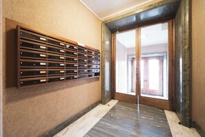 A room with a wooden storage unit against the wall, a large sliding glass door, and a wooden floor.