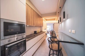 A modern kitchen with a built-in oven, microwave, and a long counter.