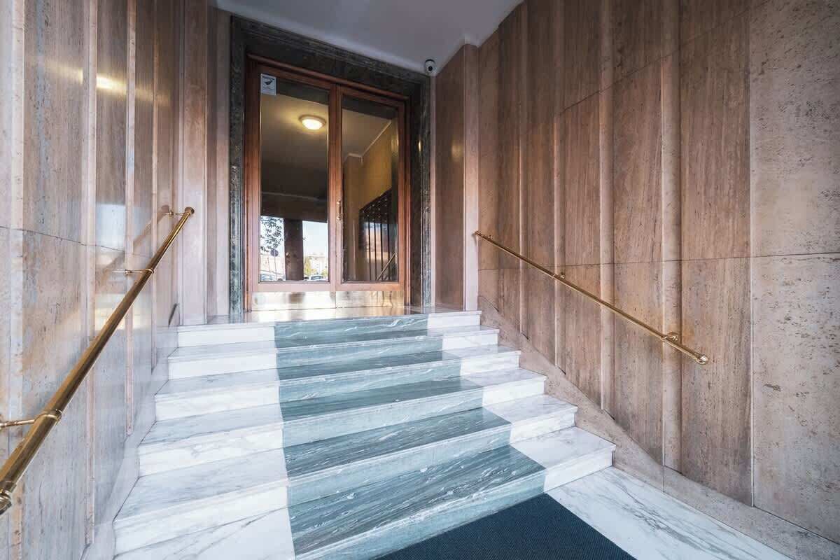 A marble staircase with a wooden wall and a glass door leading to a room.
