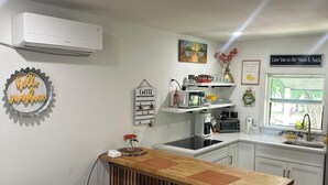 A compact kitchen with a wooden bar, a yellow table, and a trash bin. - Cool Cottage near Ennis (Rice)
