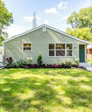 A single-story house with a front porch, a small garden, and a visible utility pole.