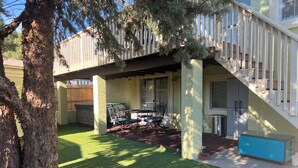 Un patio couvert avec un barbecue, des sièges d’extérieur et une petite table.