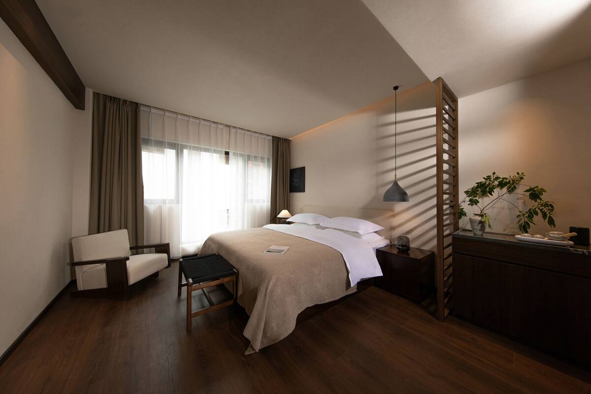 Una habitación de hotel moderna con una cama grande, un escritorio, una silla y una planta.