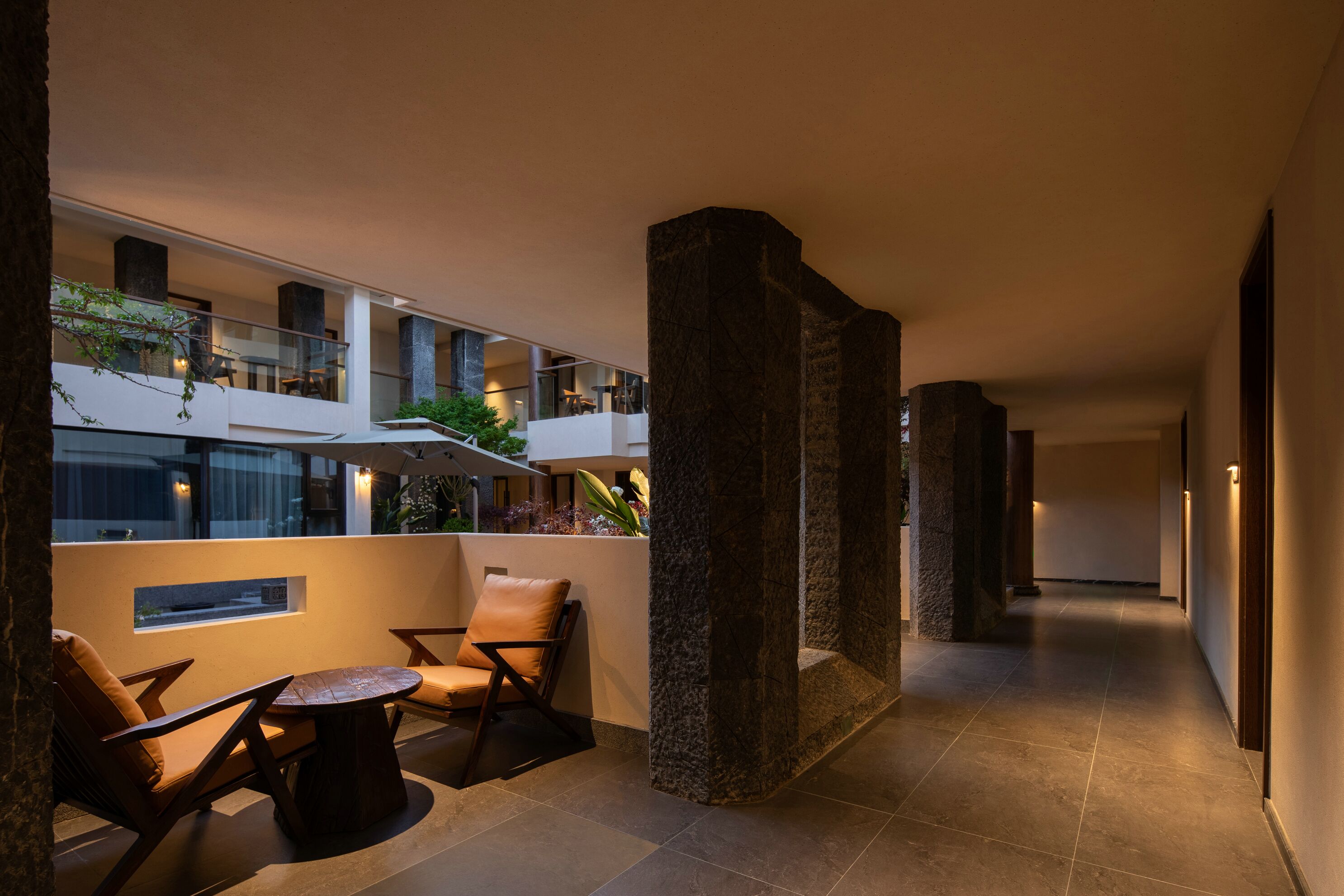 A modern hotel lobby with a spacious seating area, a high ceiling, and a view of the upper floors.