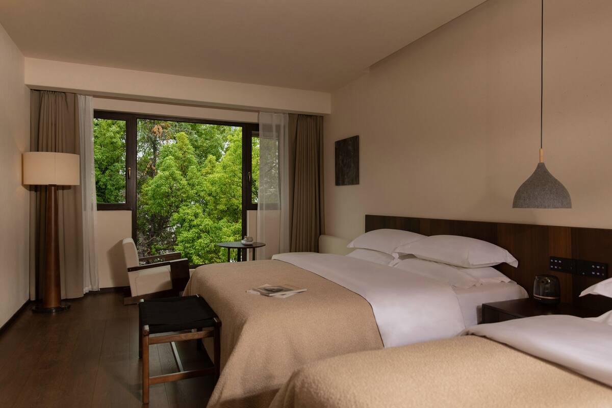 Una habitación de hotel con un ventanal grande, una cama, un escritorio y una silla.