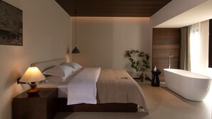 Un dormitorio moderno con una cama grande, una lámpara de noche y una bañera separada.