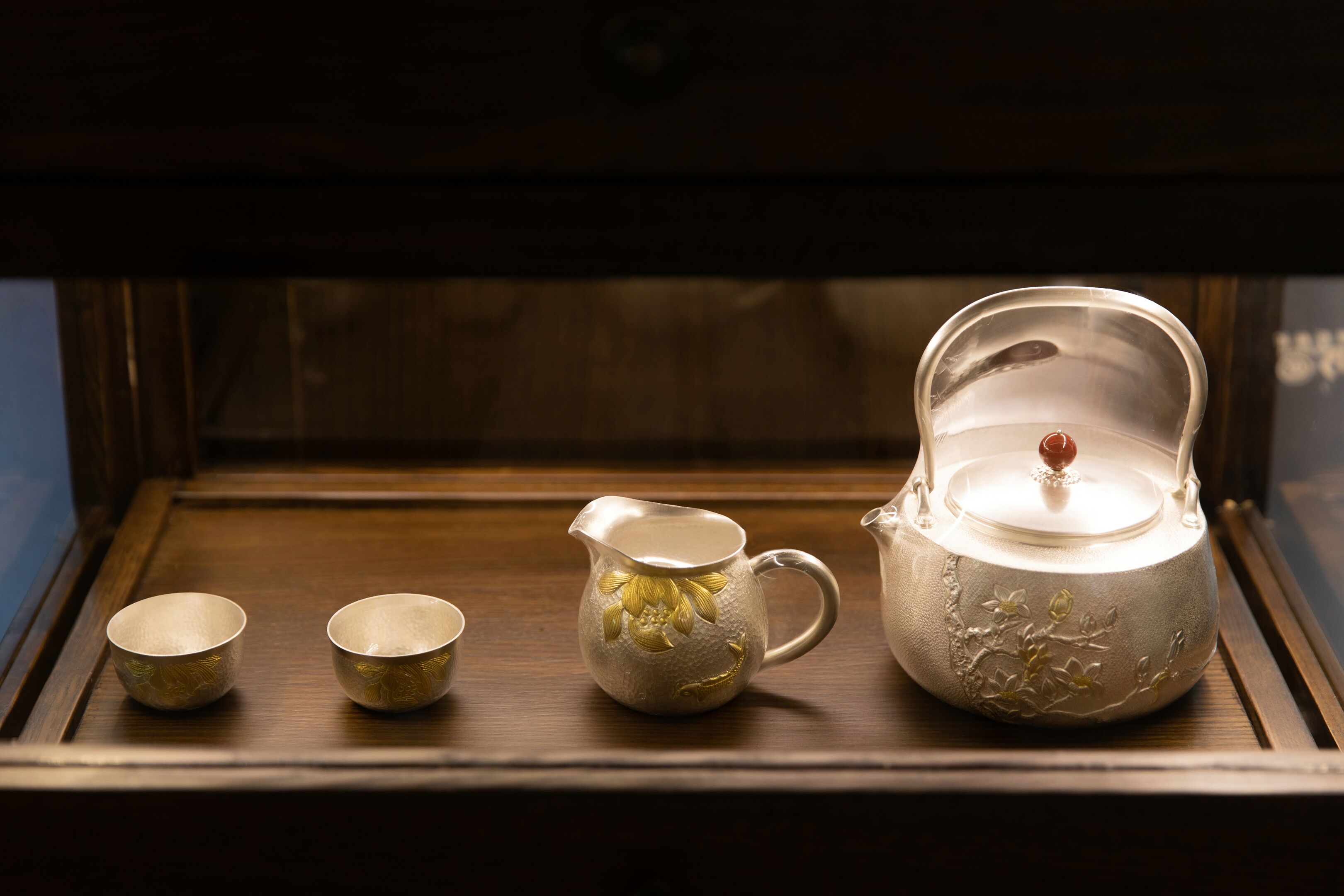 A display case containing a teapot and three cups.