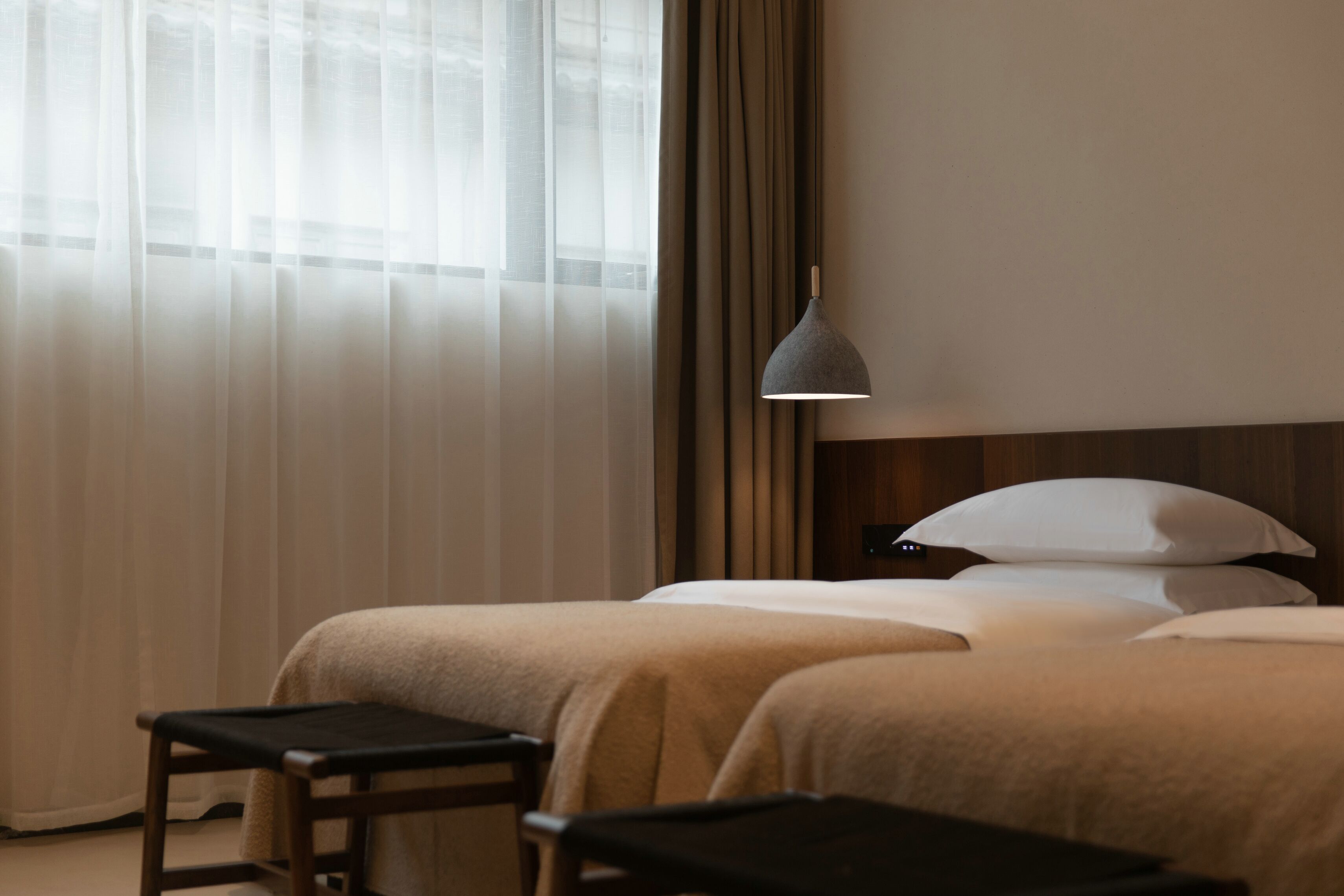 Ein Hotelzimmer mit zwei Betten, einem kleinen Tisch und einer Hängelampe.