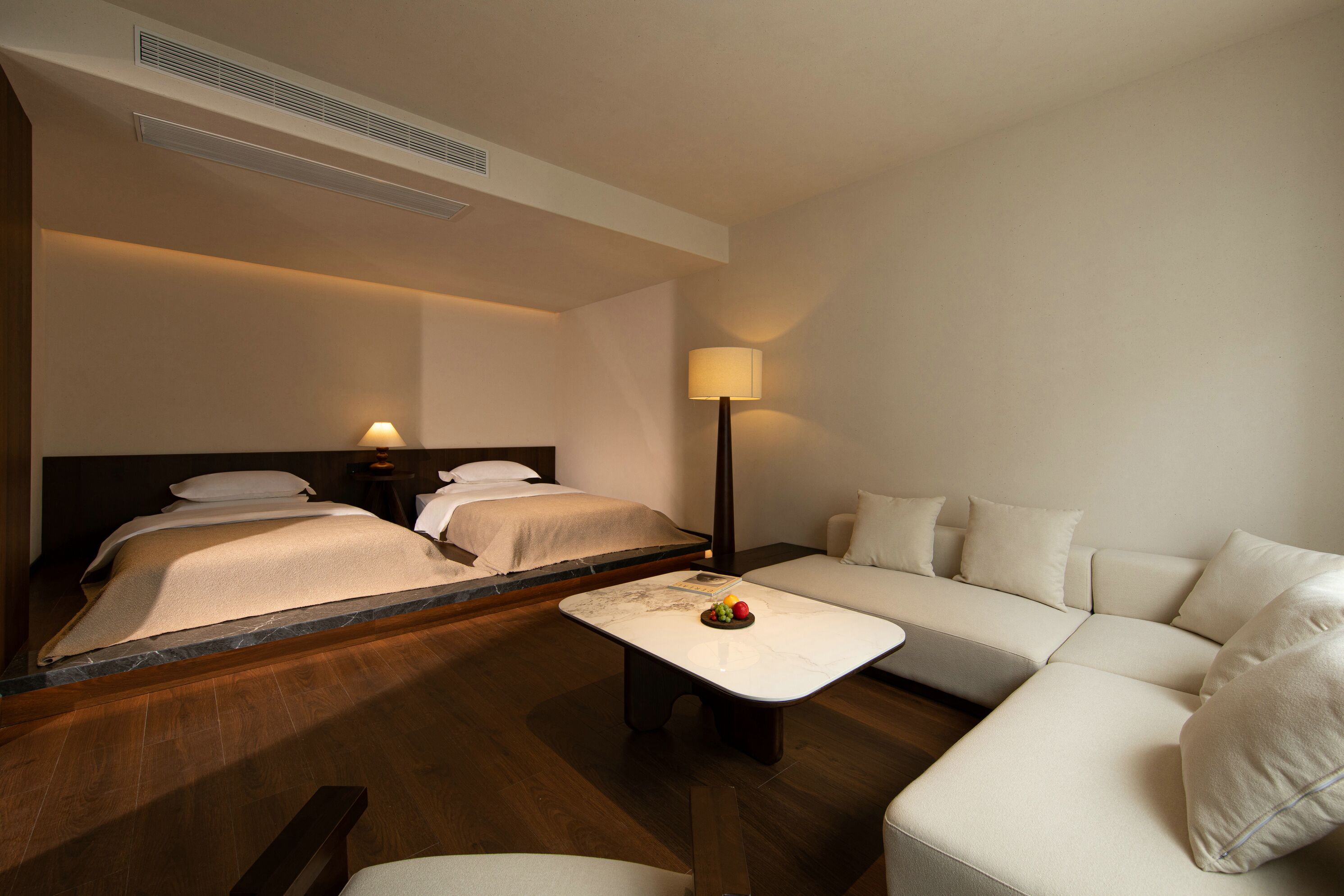Ein Hotelzimmer mit Bett, Sofa, einem kleinen Tisch mit Obst und einer Lampe.