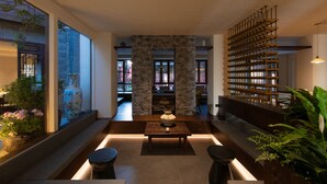 Un interior moderno con una chimenea de piedra, una estantería de madera y una zona de estar con una mesa y sillas.