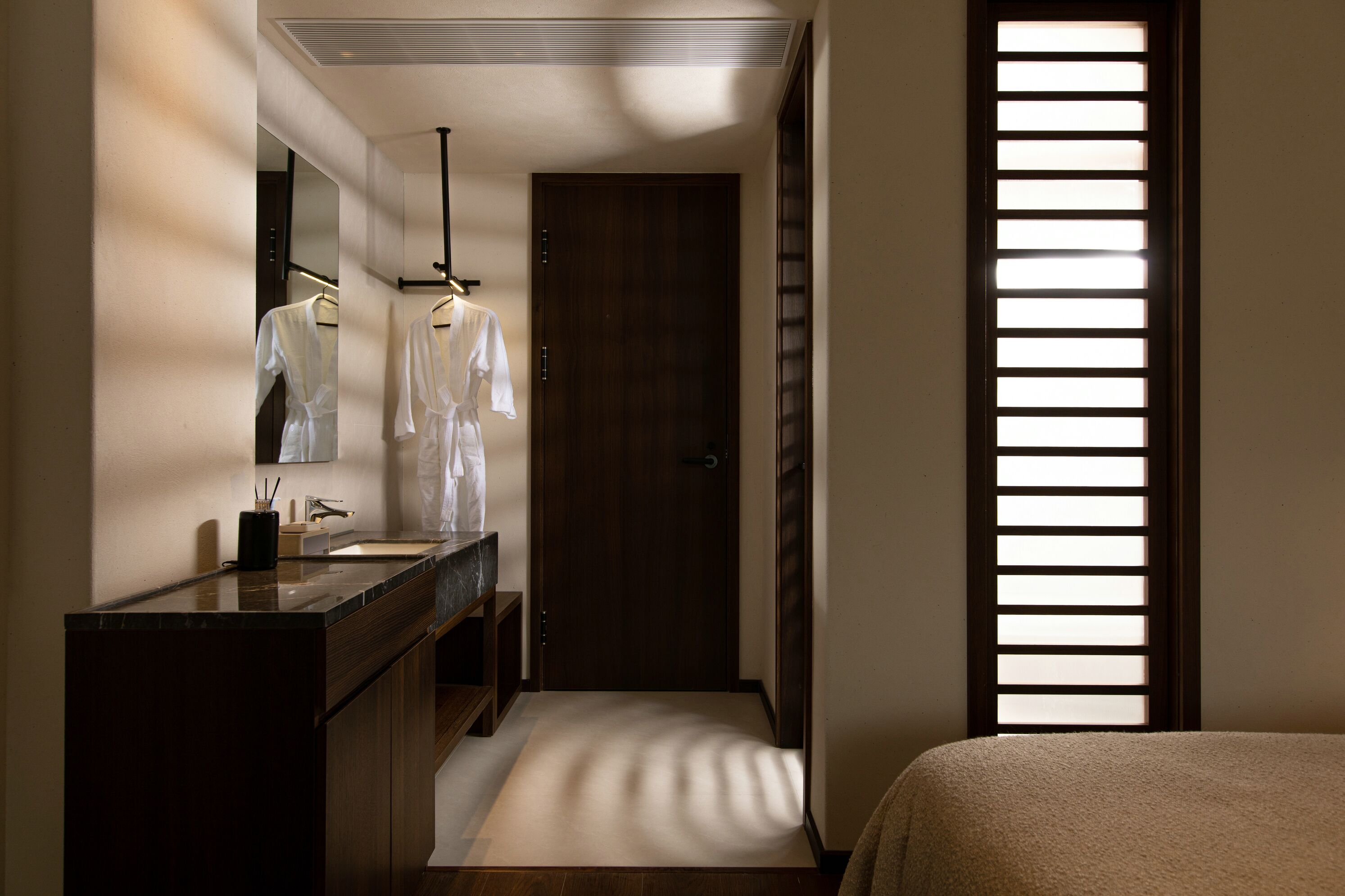 A modern bathroom with a dark wood vanity, a large mirror, and a walk-in shower.