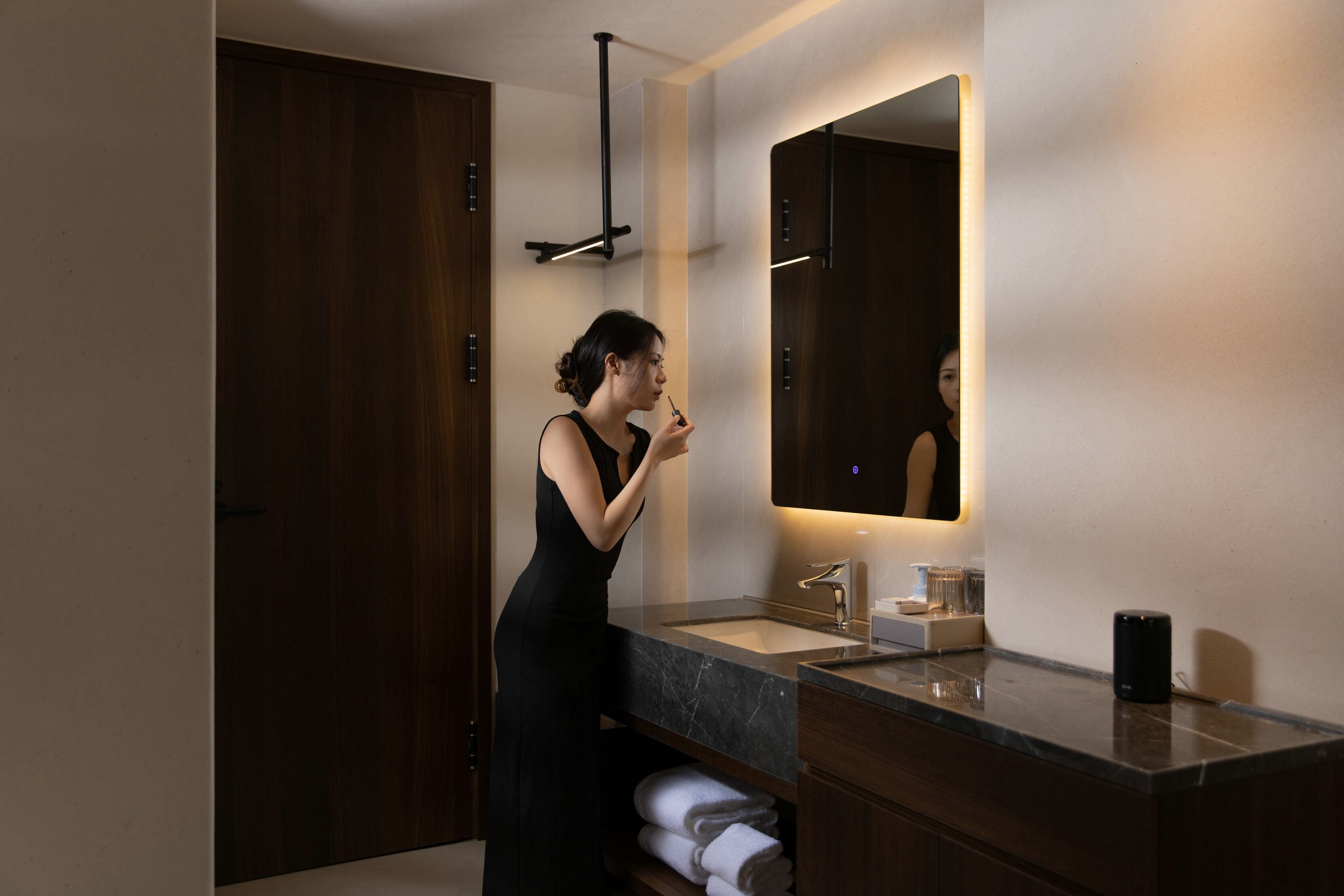 A modern bathroom with a dark wood vanity, a large mirror, and a built-in towel rack.