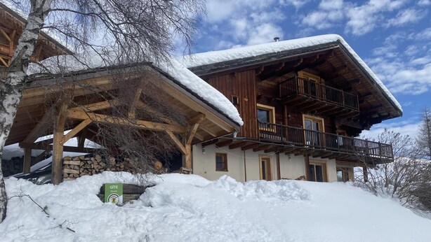 Un chalet en bois doté d’un balcon, entouré de neige.
