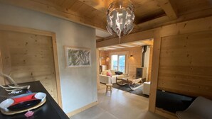 Un intérieur en bois comprenant une table à manger, des chaises, une cheminée et un luminaire suspendu.