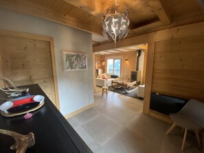 Ein Holzinterieur mit Esstisch, Stühlen, Kamin und einer hängenden Leuchte.