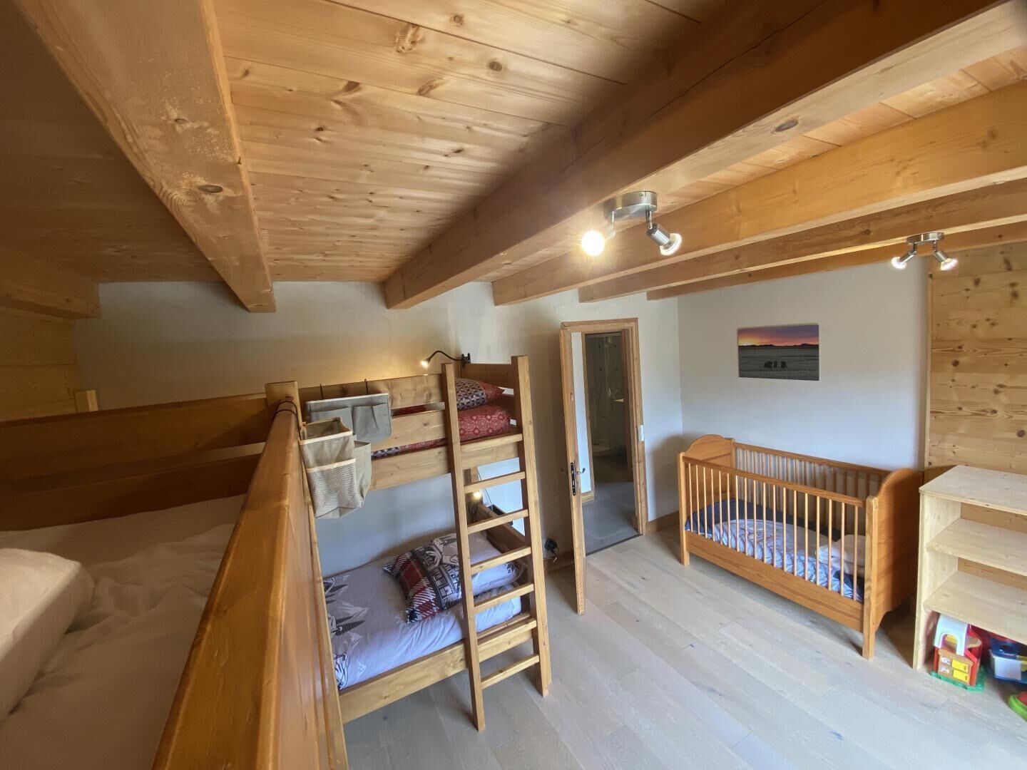 A wooden interior with bunk beds, a crib, and a ladder.