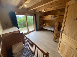 Eine Hütte mit Etagenbett, einem Holztisch und einem großen Fenster.