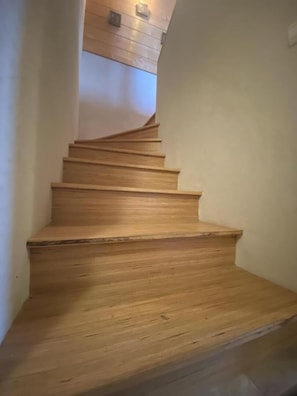 Una escalera de madera con barandilla, que conduce a una plataforma con techo de madera.