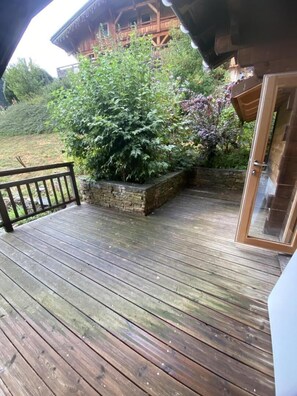 Eine Holzterrasse mit einem Steingarten und einer Glastür, die zu einem Gebäude führt.