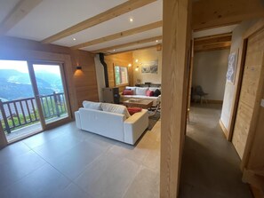 A spacious living area with a white sofa, a dining table, and a view of the outdoors. - CHALET HAUT 6 - HAUTELUCE LES SAISIES (HAUTELUCE LES SAISIES)