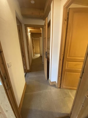 Un pasillo con puertas de madera y suelo de baldosas.