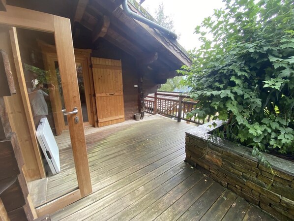 Una terraza de madera con un muro de piedra y una puerta de madera que da a una habitación.