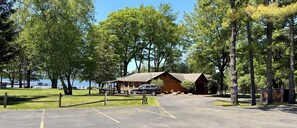 A cabin with a wooden exterior, a paved driveway, and a parking area with marked spaces.