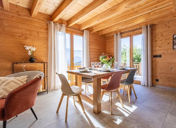 A wooden cabin with a dining area, a sofa, and a table set for four.