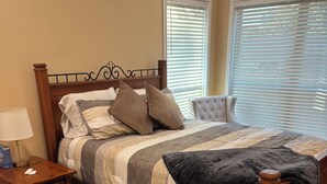 A bedroom with a wooden bed, a nightstand, a lamp, and a patterned rug. - Welcoming 6-bedroom house with country living in the shadow of Kyle Field (College Station)