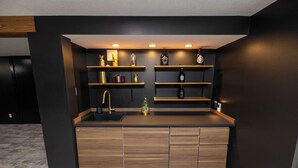 Eine moderne Küche mit Holzausstattung, einer schwarzen Arbeitsplatte und eingebauten Regalen mit verschiedenen Küchenutensilien.