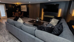 Ein modernes Wohnzimmer mit einem grauen Ecksofa, einem Couchtisch und einem flachbildfernseher an der Wand.