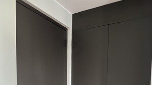Un armario de color oscuro con marco de puerta blanco y un tirador plateado.