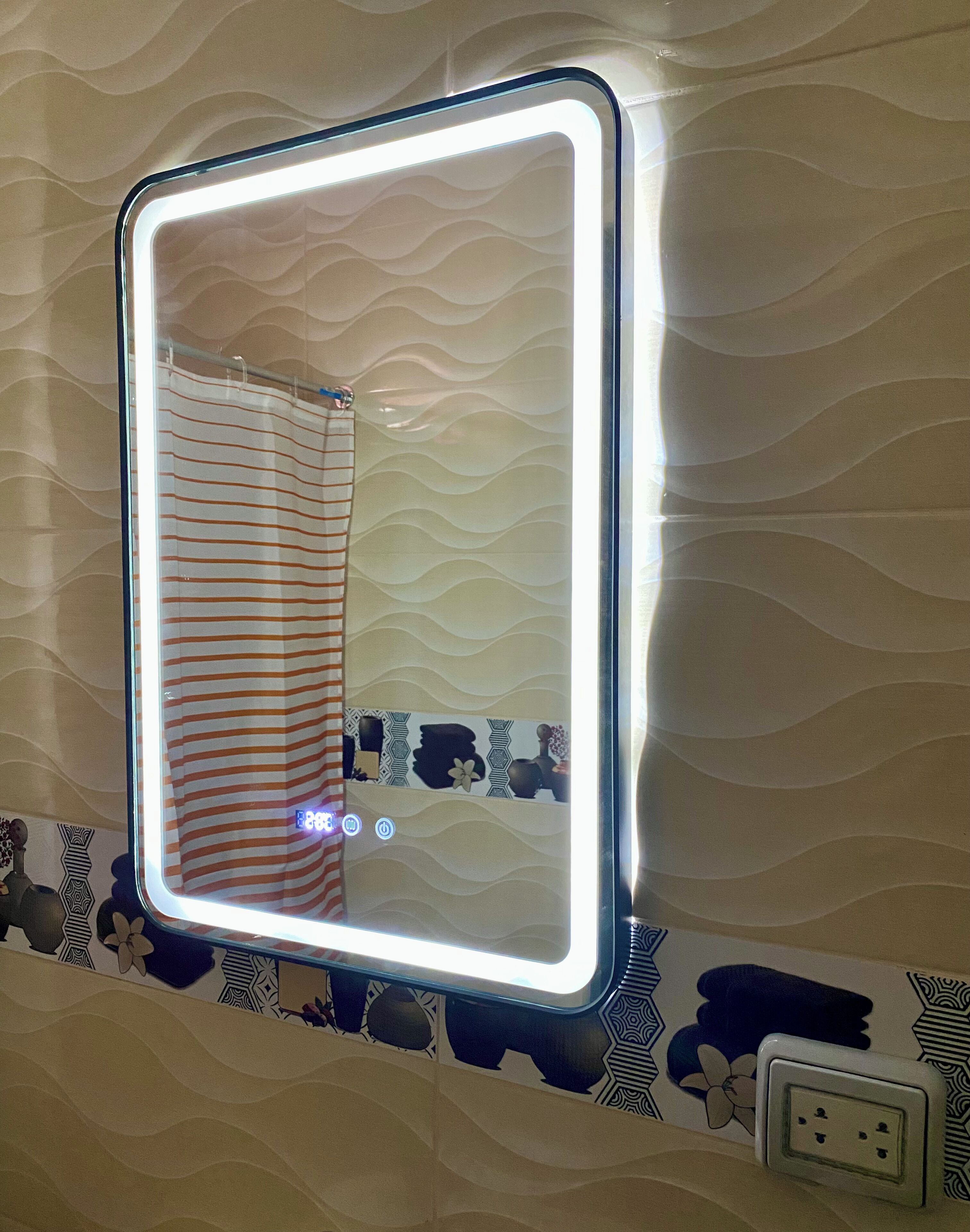 A bathroom with a wall-mounted mirror, striped shower curtain, and patterned wall tiles.
